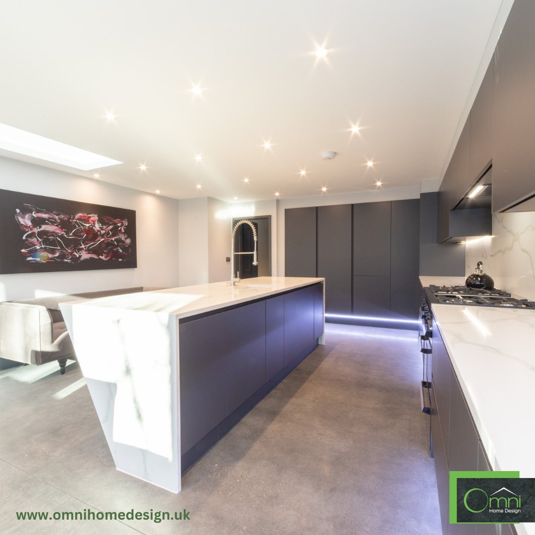 A dark graphite handleless kitchen with a waterfall quartz island and LED lighting under the units