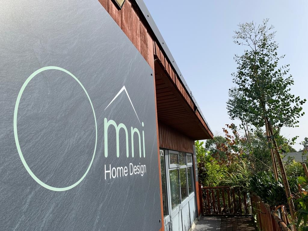 The Omni Home Design logo on a slate-effect sign fixed to a timber-clad building